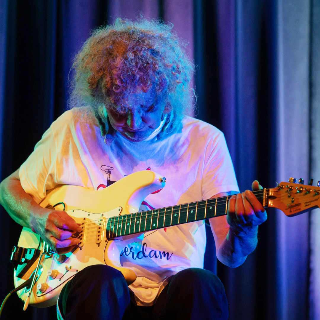 A photo of Armin Pokorn playing a white Fender Squier guitar